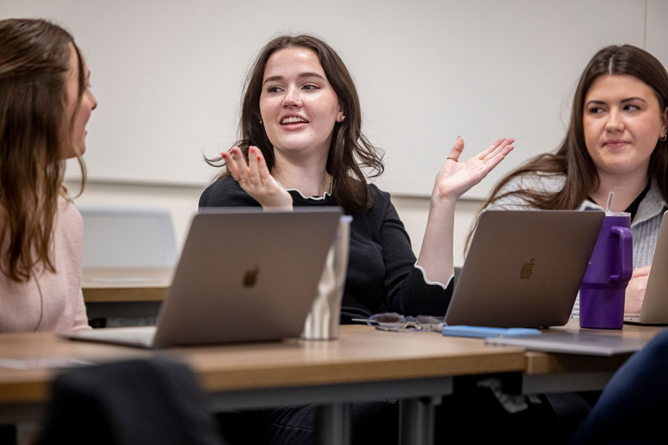 Three students discussing a topic in class