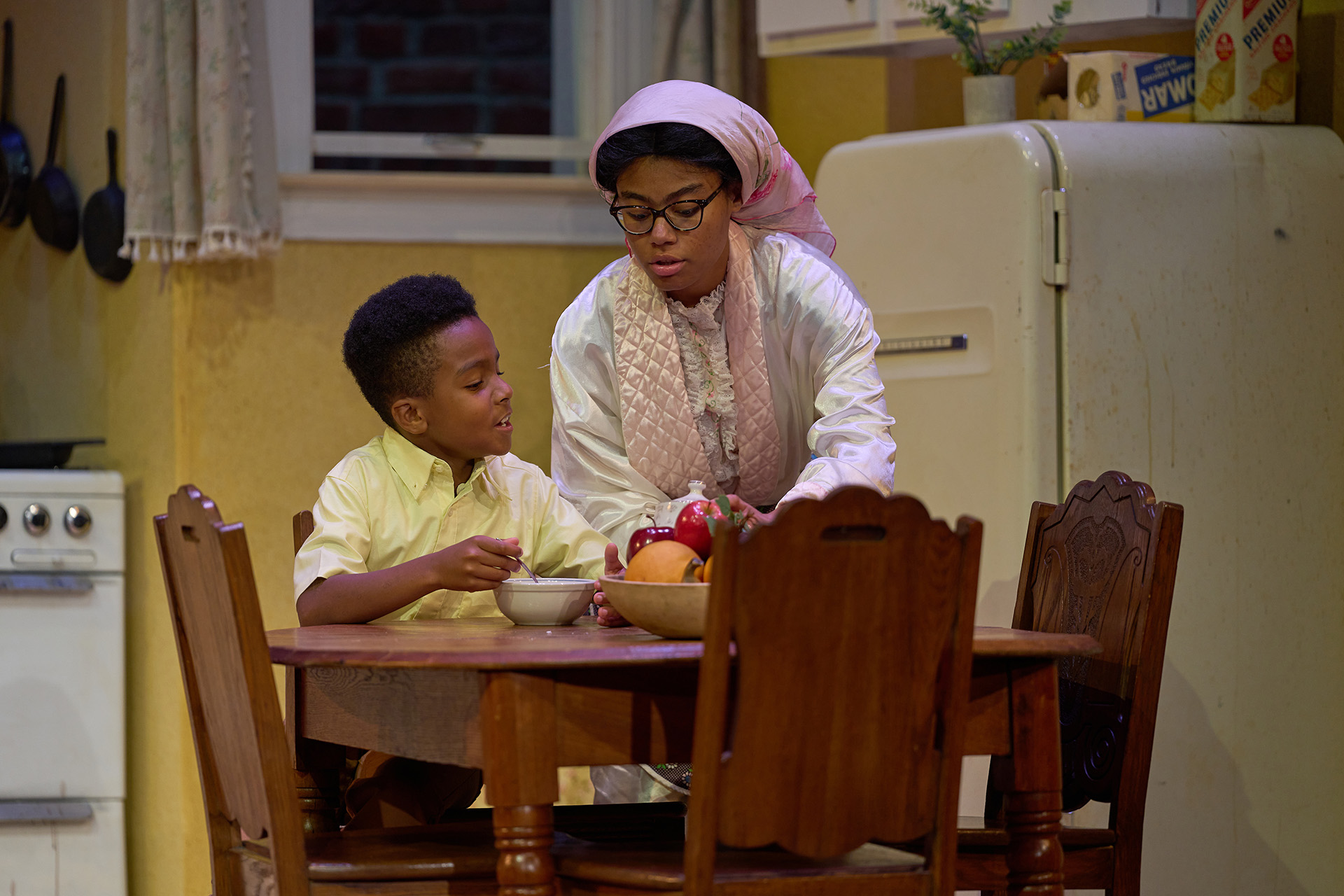 A Black child and his mother sit at the breakfast table