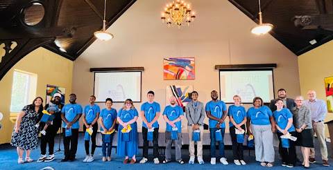 About 12 program participants wearing matching t-shirts, stand in a row, with faculty members on the side.