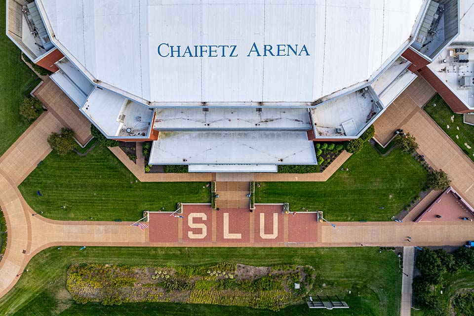 Aerial photo of chaifetz arena with bricks that spell out "SLU" on the path in front of it.