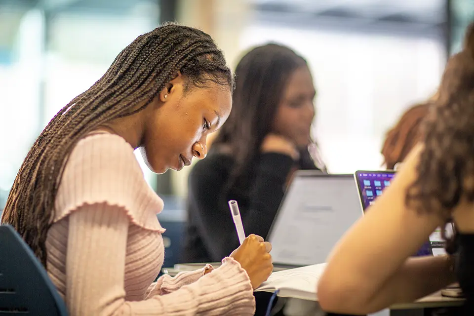 Two students sitting at a table with a laptop in the library.