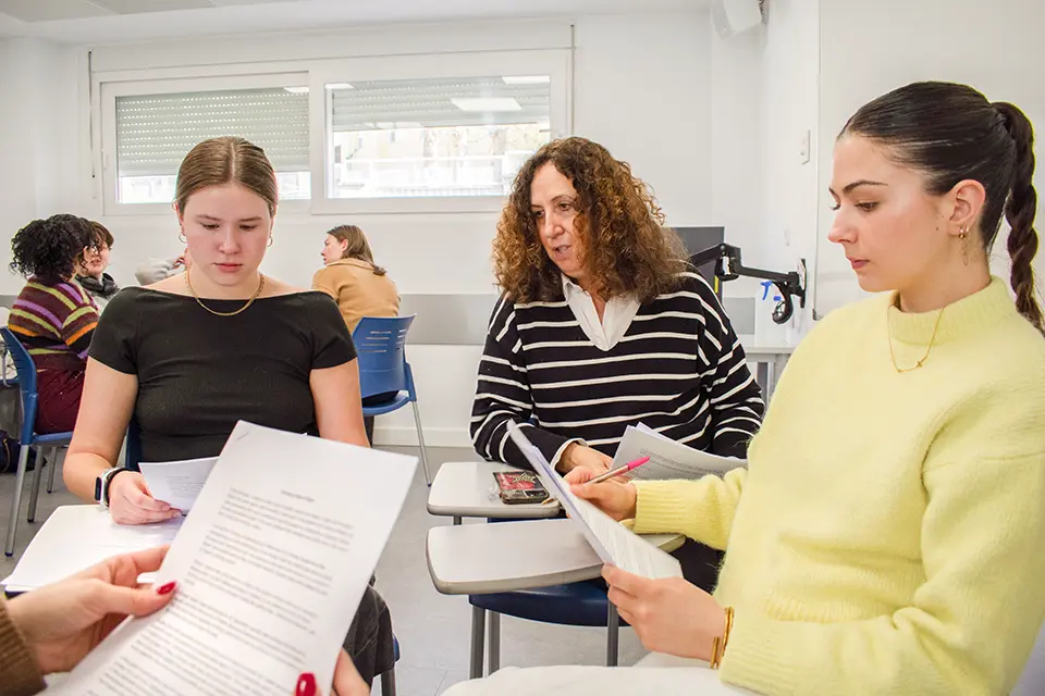 Students with professor looking at his laptop.