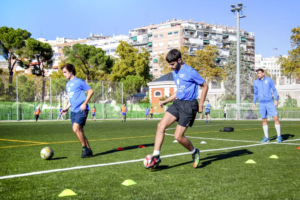 Three students play soccer on a field outside.