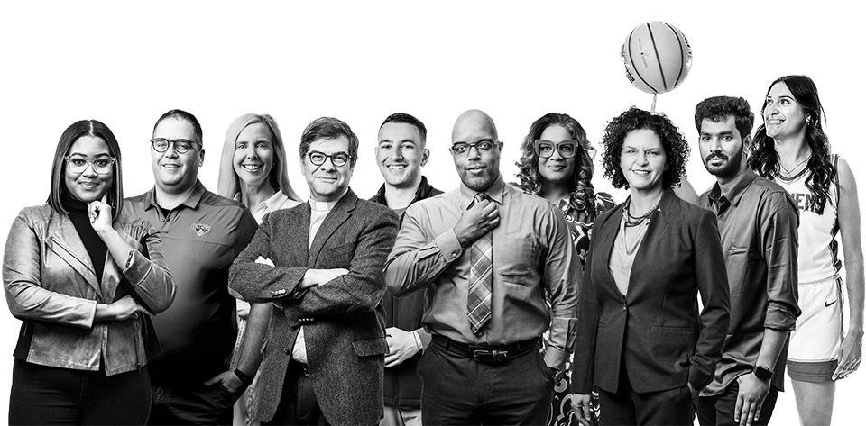 A diverse group of individuals smiling and posing for a black-and-white photo together.