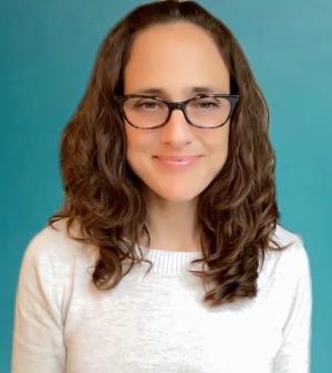 A white woman with shoulder-length brown hair and glasses. Her smile is friendly, but not so friendly that you would stop by her office without an appointment.